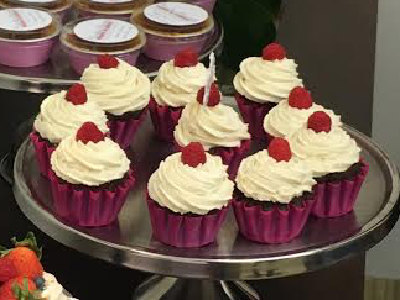 Cupcakes with white cream and raspberries on a cake stand