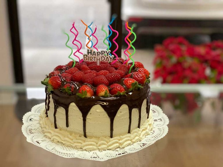 Keto buttercream cake with chocolate ganache drip and fresh strawberries