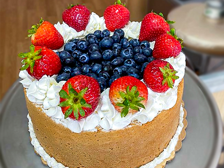 Tres leches cake topped with whipped cream, strawberries and blueberries