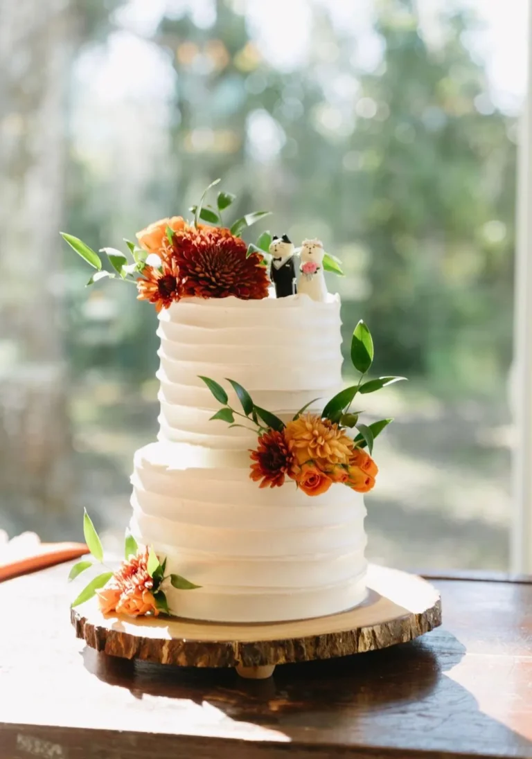 Two-tier ribbed cake with autumn flowers on a wood slice
