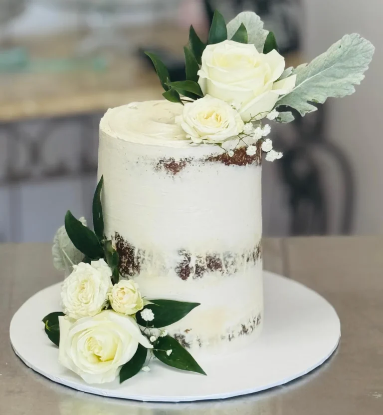 Tall semi-naked cake with white roses and dusty miller