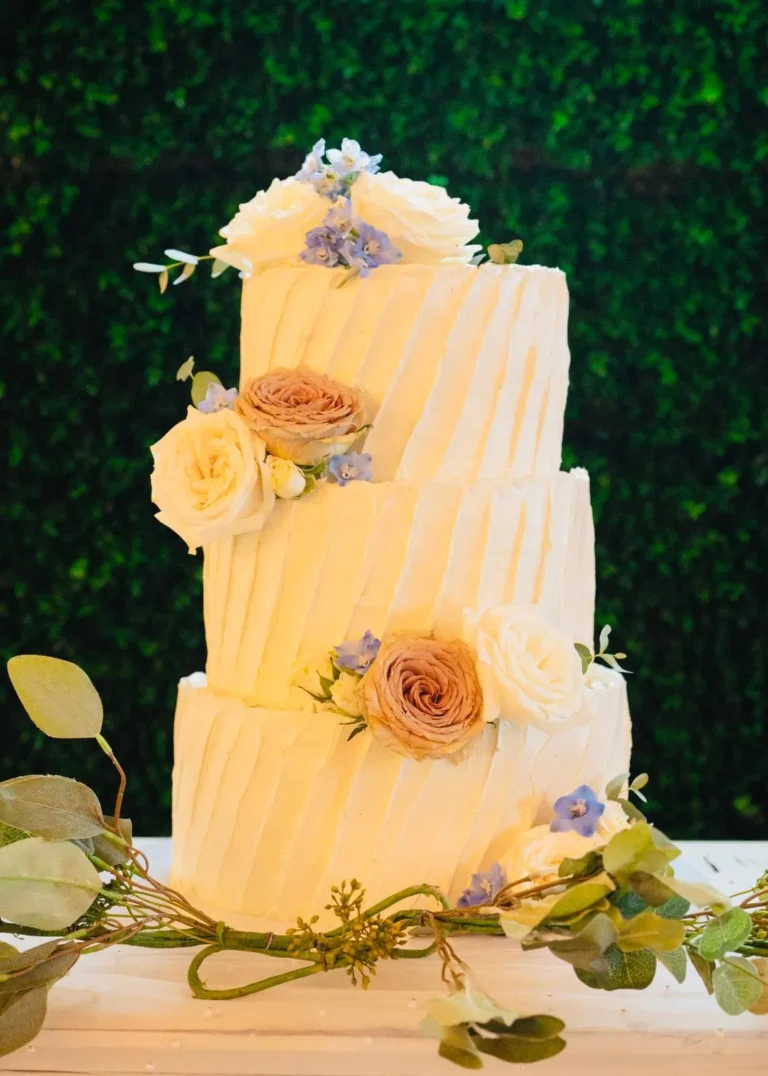 Three-tier textured buttercream cake with peach roses and greenery