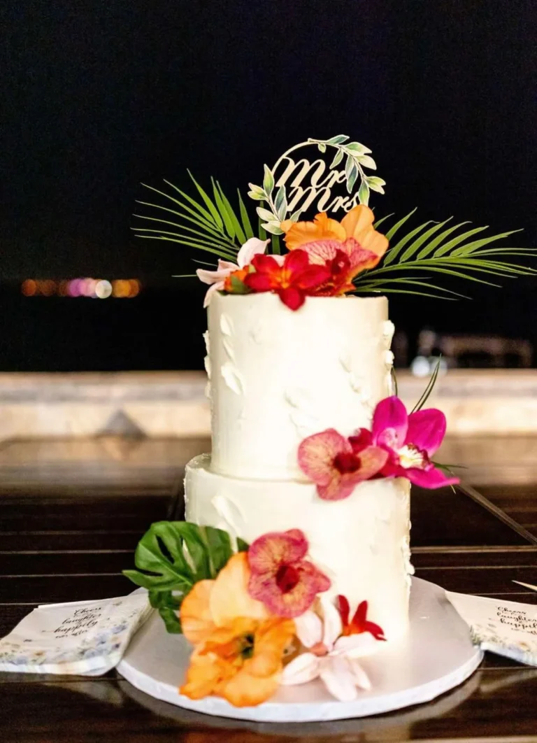 Two-tier white wedding cake with tropical flowers and a Mr and Mrs topper
