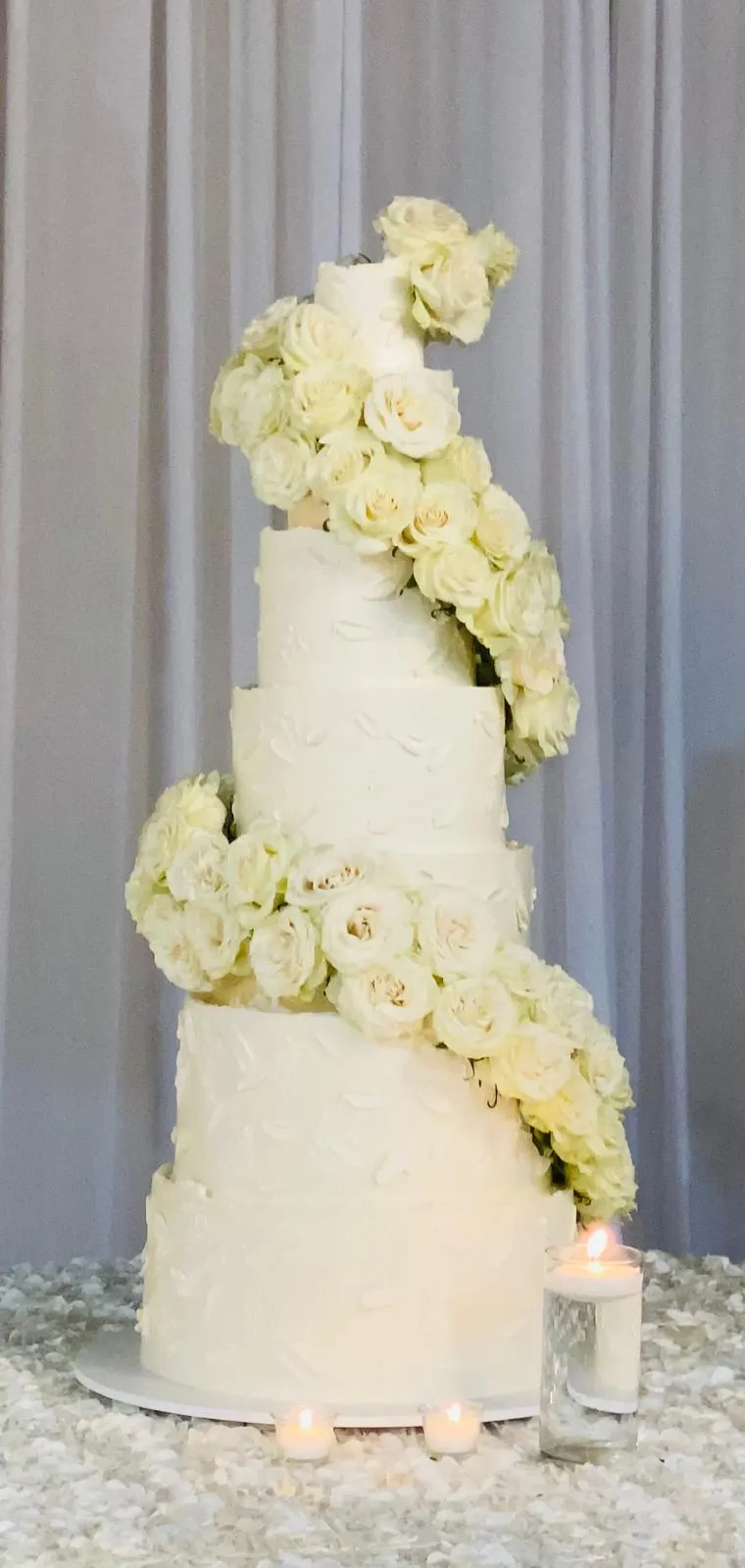 Five-tier white wedding cake with a spiral of white roses