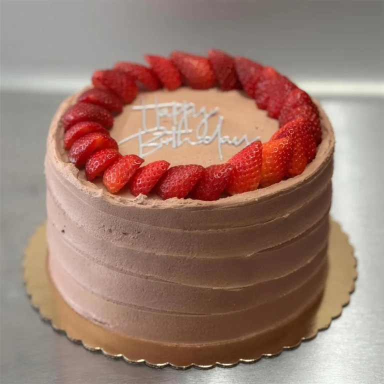 Chocolate buttercream birthday cake with a ring of fresh strawberries