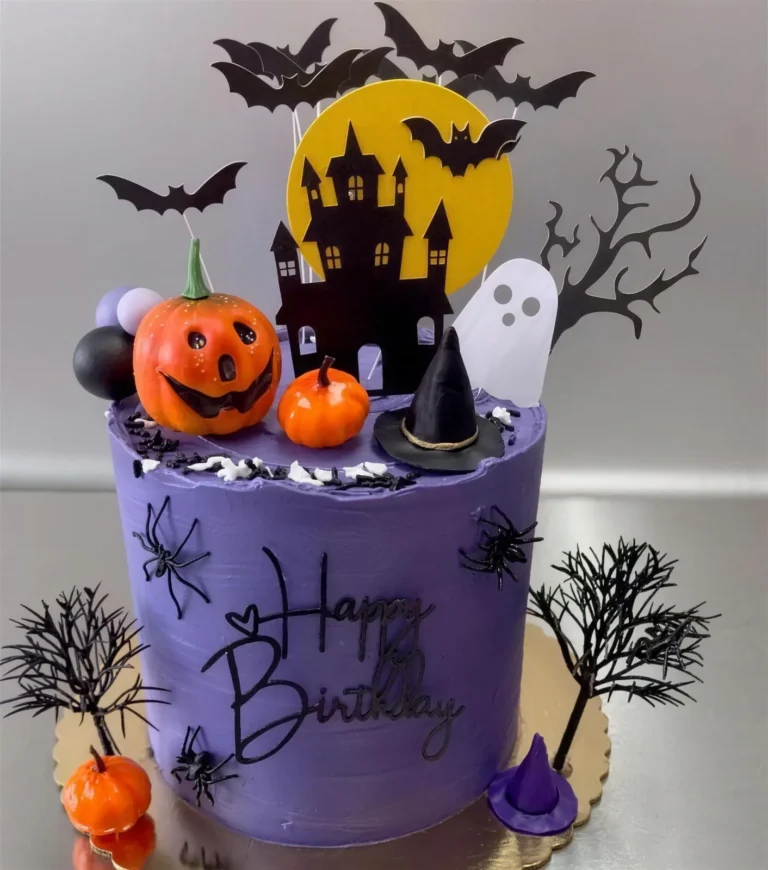 Purple Halloween birthday cake with a haunted house, pumpkins and bats