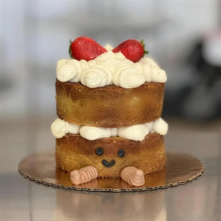 Small two-layer naked cake with cream, strawberries and a smiling face
