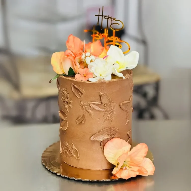 Tall mocha buttercream birthday cake with palette-knife petals and fresh peach and white flowers