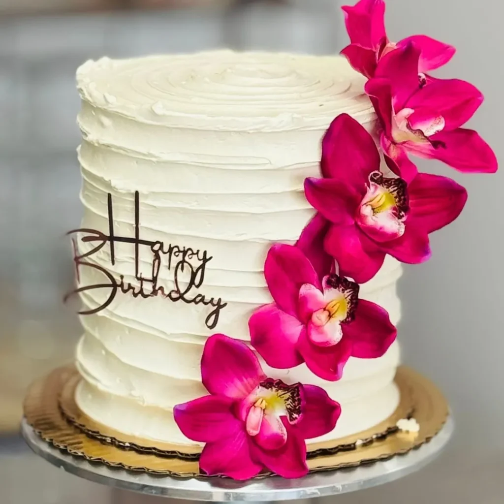 White ribbed buttercream birthday cake with a cascade of pink orchids